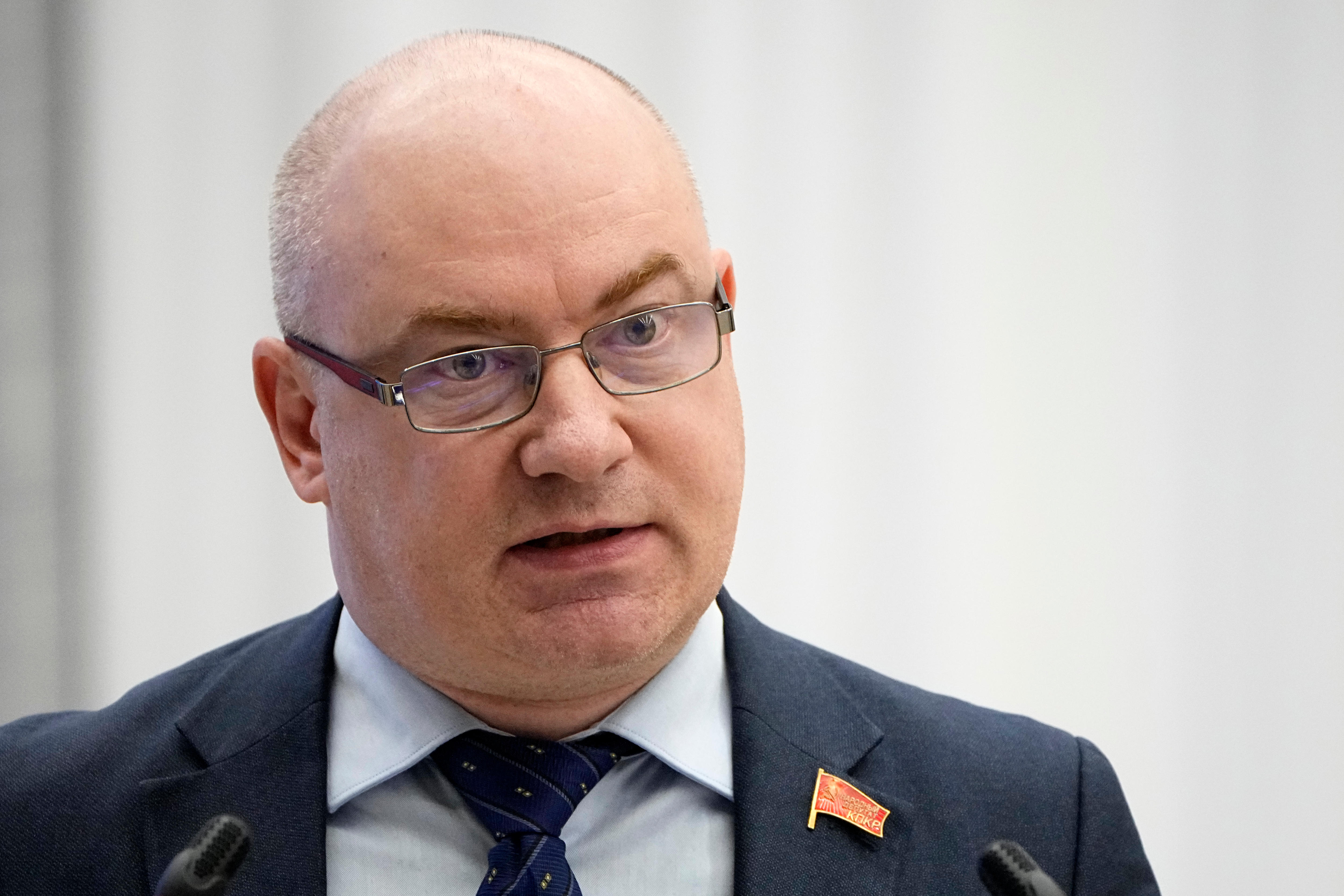 A man in a suit with a communist flag pin on his lapel 