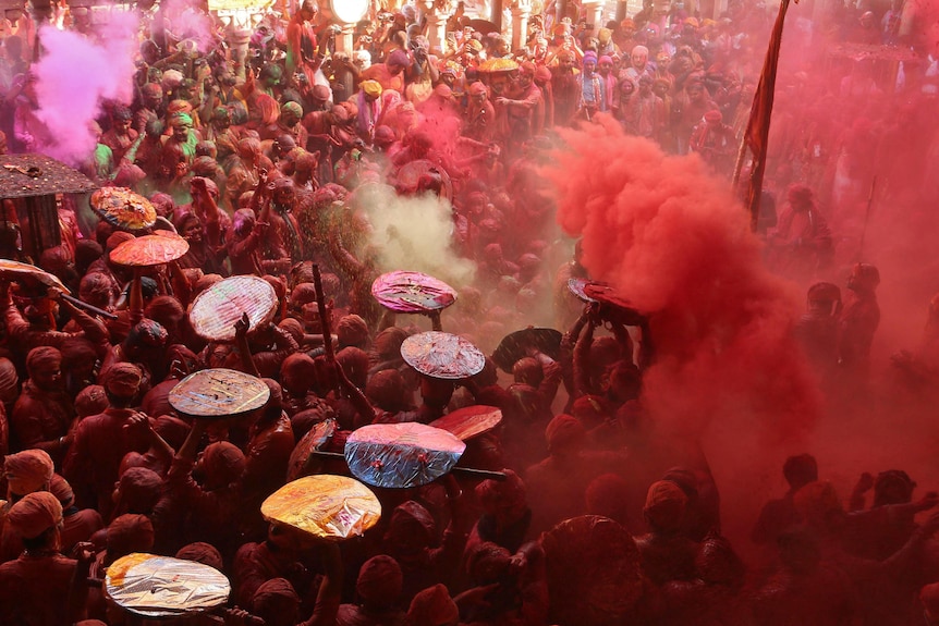 Men daubed in colours throw coloured powder at each other during celebrations inside a temple in India.