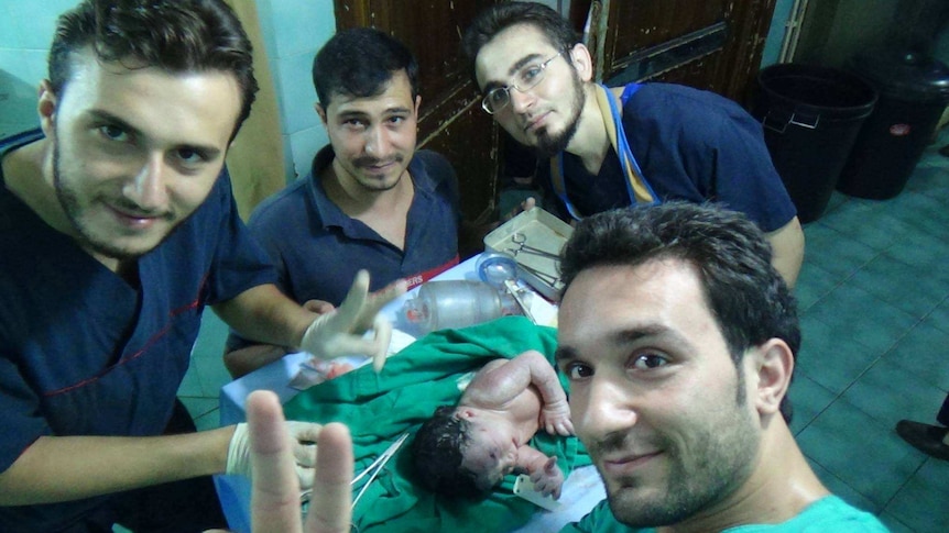 Doctors pose with baby injured by shrapnel in utero