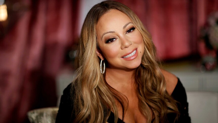 Mariah Carey smiles and tilts her head to the side as she poses for a portrait.