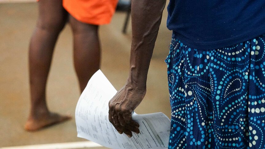 A woman holds papers in her hand