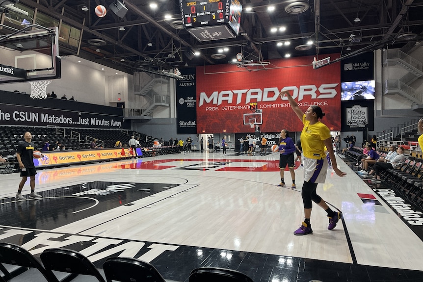 Australian basketballer Liz Cambage holds her hand out as she watches her shot head toward the basket in training.