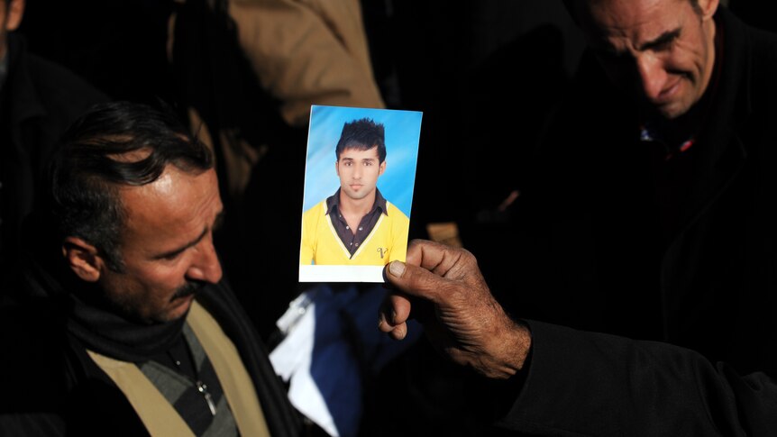Kurdish man Hamit Encu holds a picture of his son who was killed in a Turkish air raid.