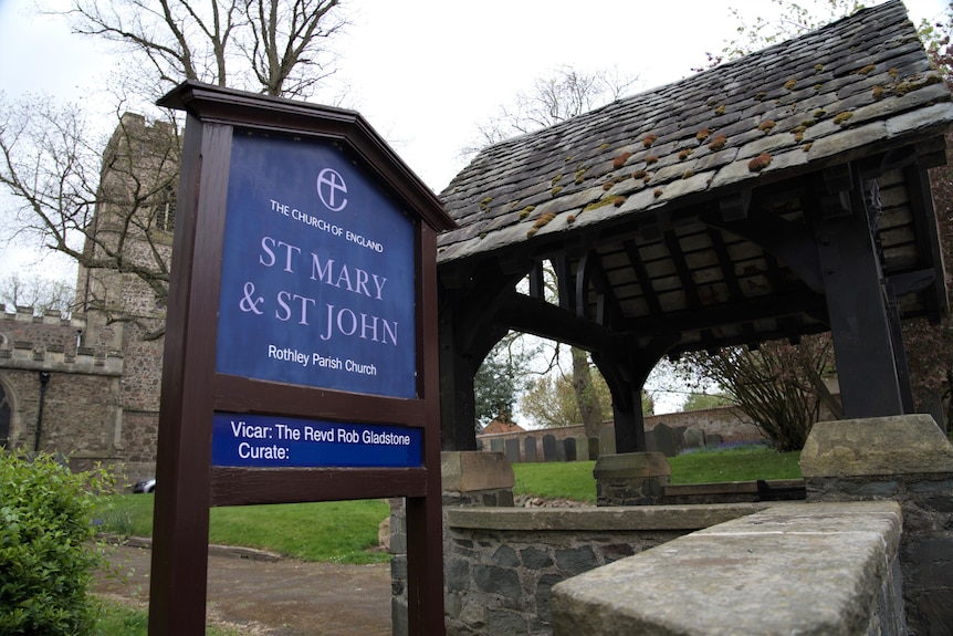 A sign displaying St Mary and St John's stands near an entrance to a church.