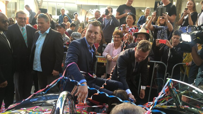 Jeff Horn is covered in streamers sitting on top a vintage car during his ticker tape parade in the Queen Street Mall