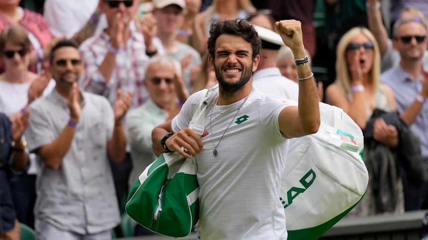 An Italian tennis player grins widely as he pumps his fist to the crowd on Centre Court after winning his Wimbledon semi=final. 