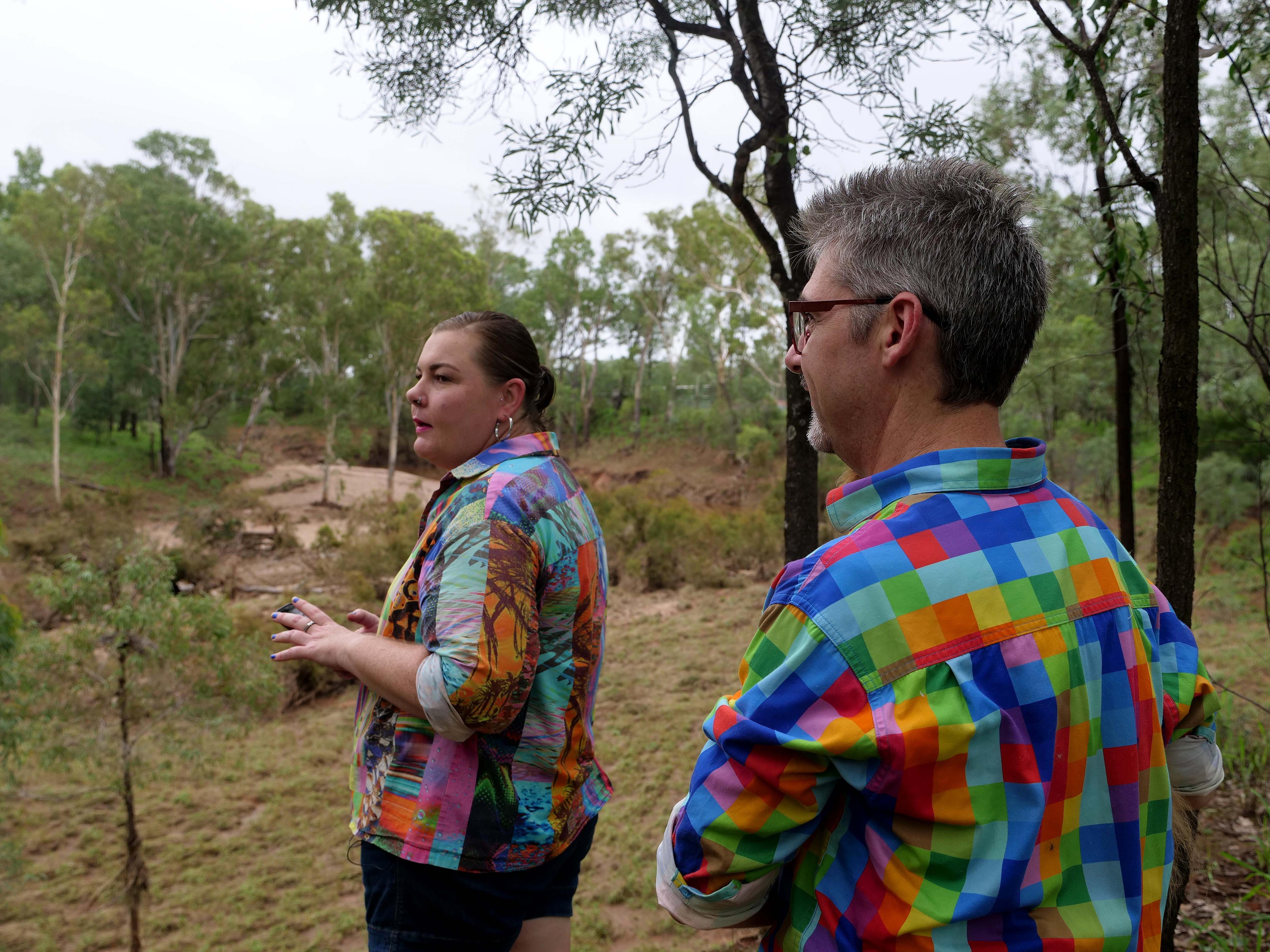 Un hombre y una mujer están afuera y miran el lecho de un arroyo.