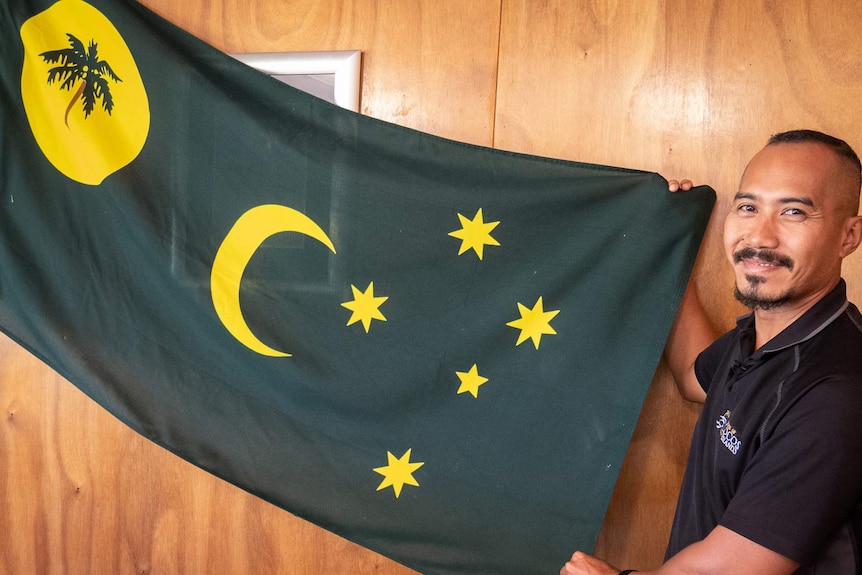 Mohammed Minkom with the Cocos Island flag he desgined as a teenager  in the 1990s.
