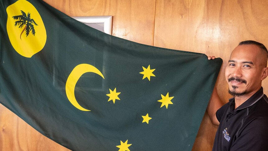 Mohammed Minkom with the Cocos Island flag he desgined as a teenager  in the 1990s.