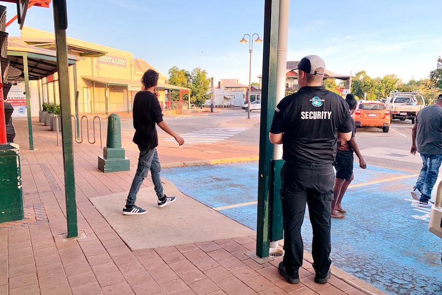 A security guard stands outside as people walk by