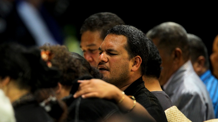 Family members console each other during the Community Prayer Gathering at the Logan Sports Centre in Crestmead