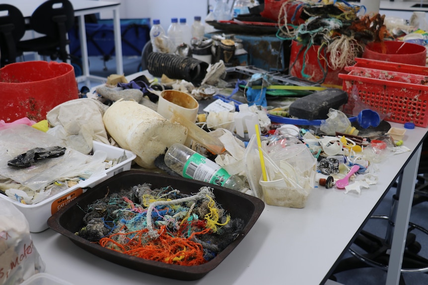Piles of rubbish including ropes, plastic bottles and PVC pipes are sprawled out on a table 