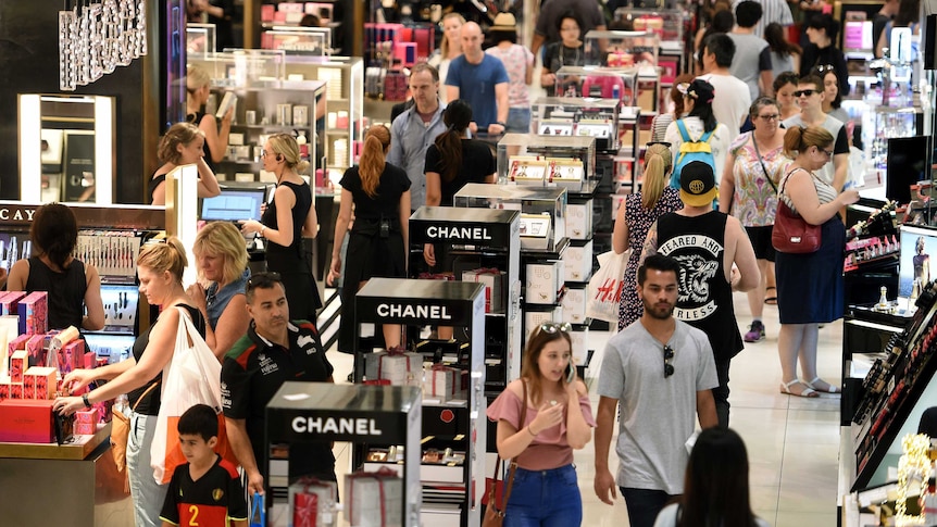 Shoppers mill around a cosmetics section in a department store