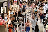 Shoppers mill around a cosmetics section in a department store