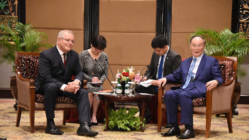 Scott Morrison and Wang Qishan sit in chairs with interpreters behind them