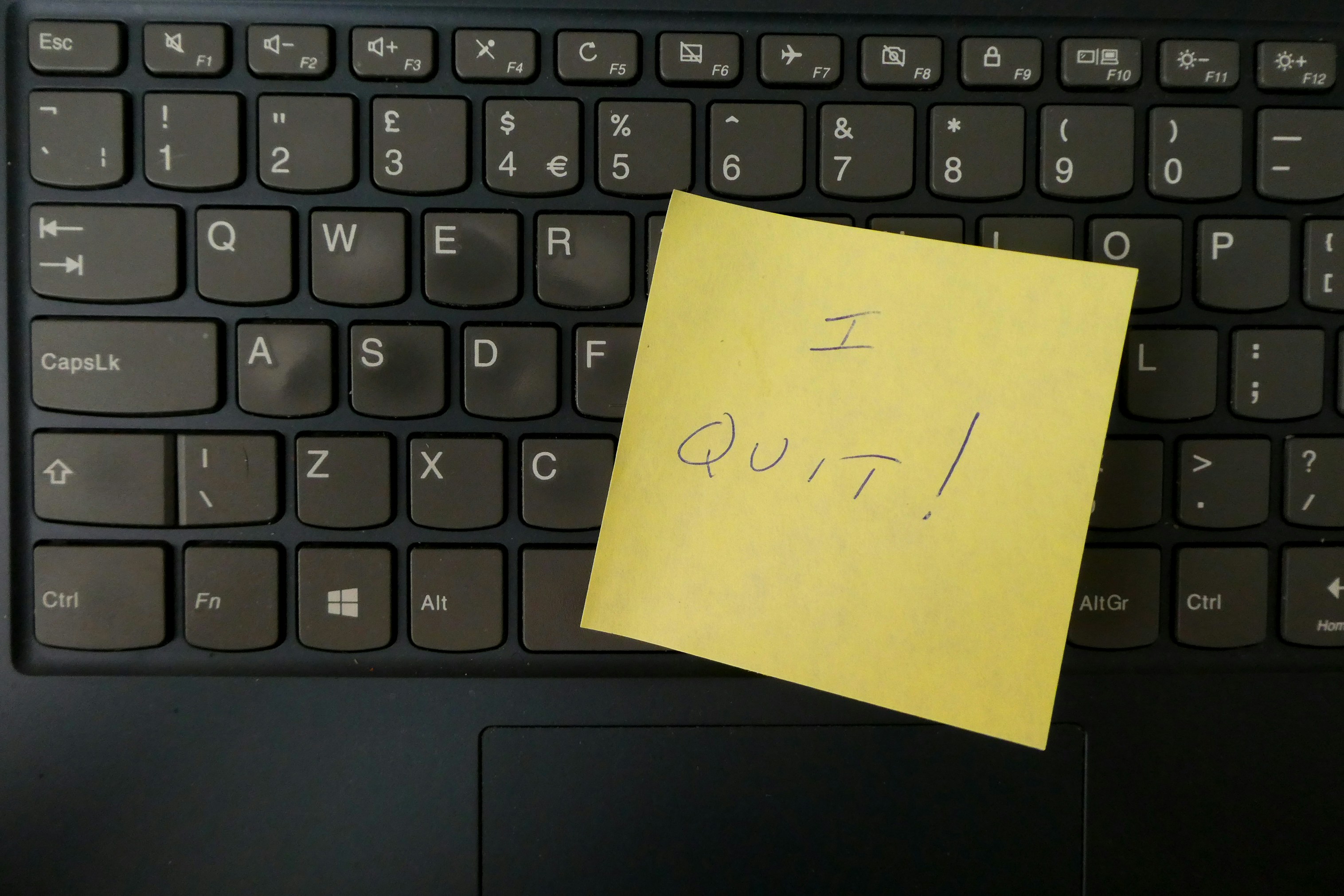 "I QUIT" written on a yellow post-it note sitting on a keyboard
