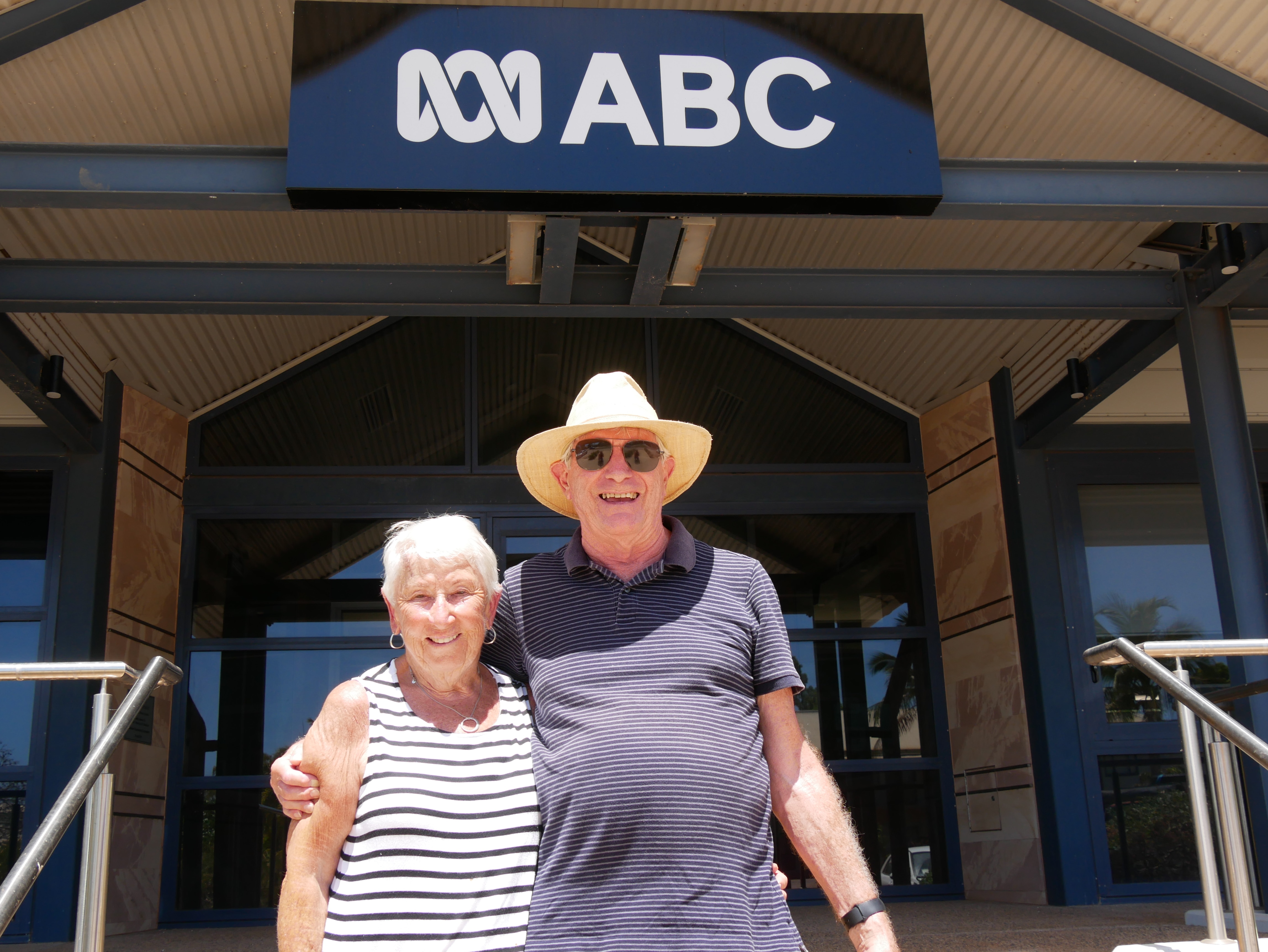An elderly couple embrace from the ABC office. 