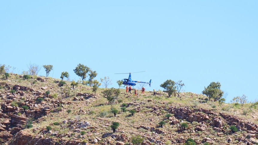 A helicopter unloads SES volunteers onto a clifftop near Lake Argyle.