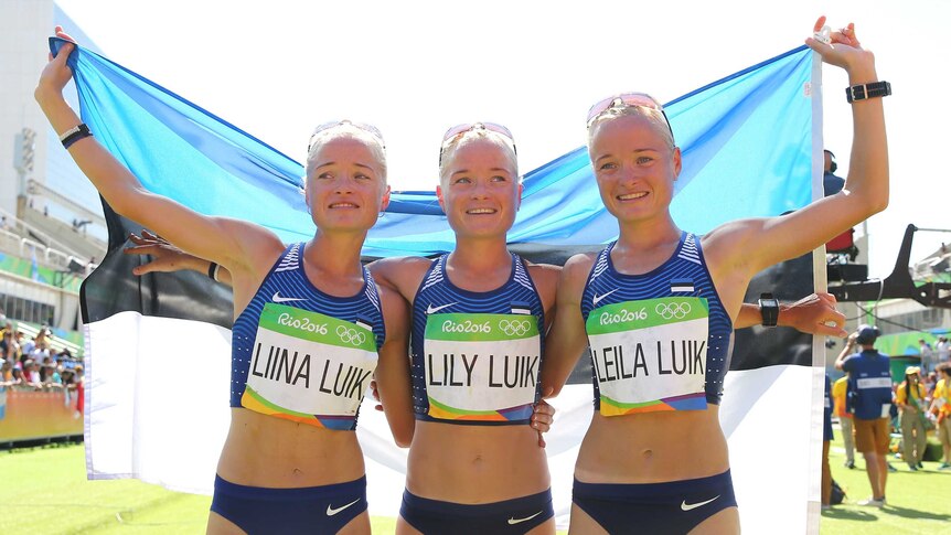 The Luik sisters hold the Estonian flag after the marathon in which they all competed