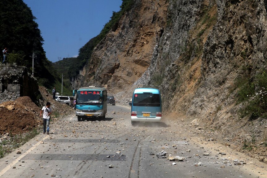 Buses navigate road covered by rocks near the Zhaotong municipality.