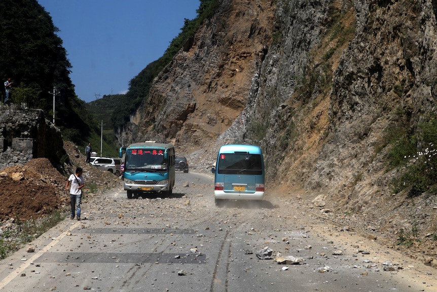Buses navigate road covered by rocks near the Zhaotong municipality.