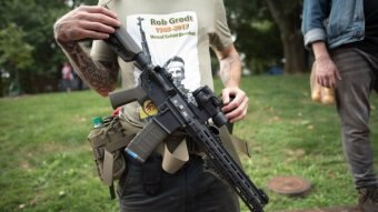 A man holding a gun with an Antifa shirt