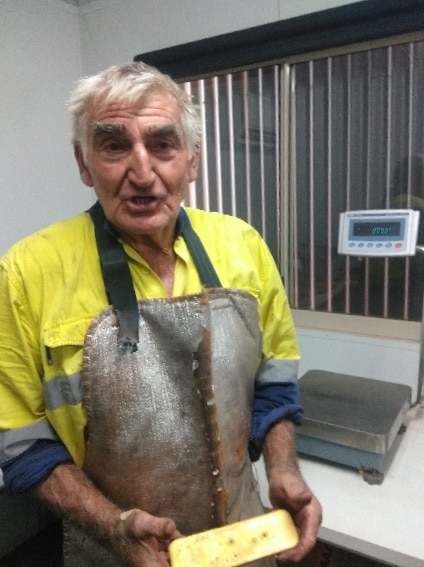 Man standing holding a gold bar.