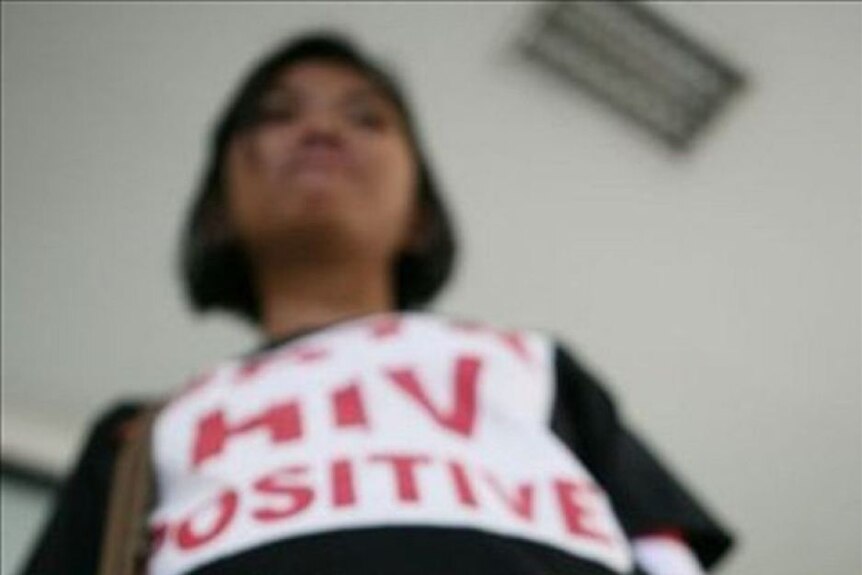 A blurry photo of a woman wearing an 'HIV-positive' shirt with red writing.
