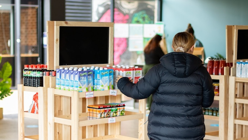 Student viewed from behind selecting grocery items from shelf