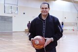 Tall man on a basketball court holding a basketball