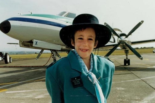 Young Eve van Grafhorst wears an Air New Zealand hostess' uniform standing in front of a plane.