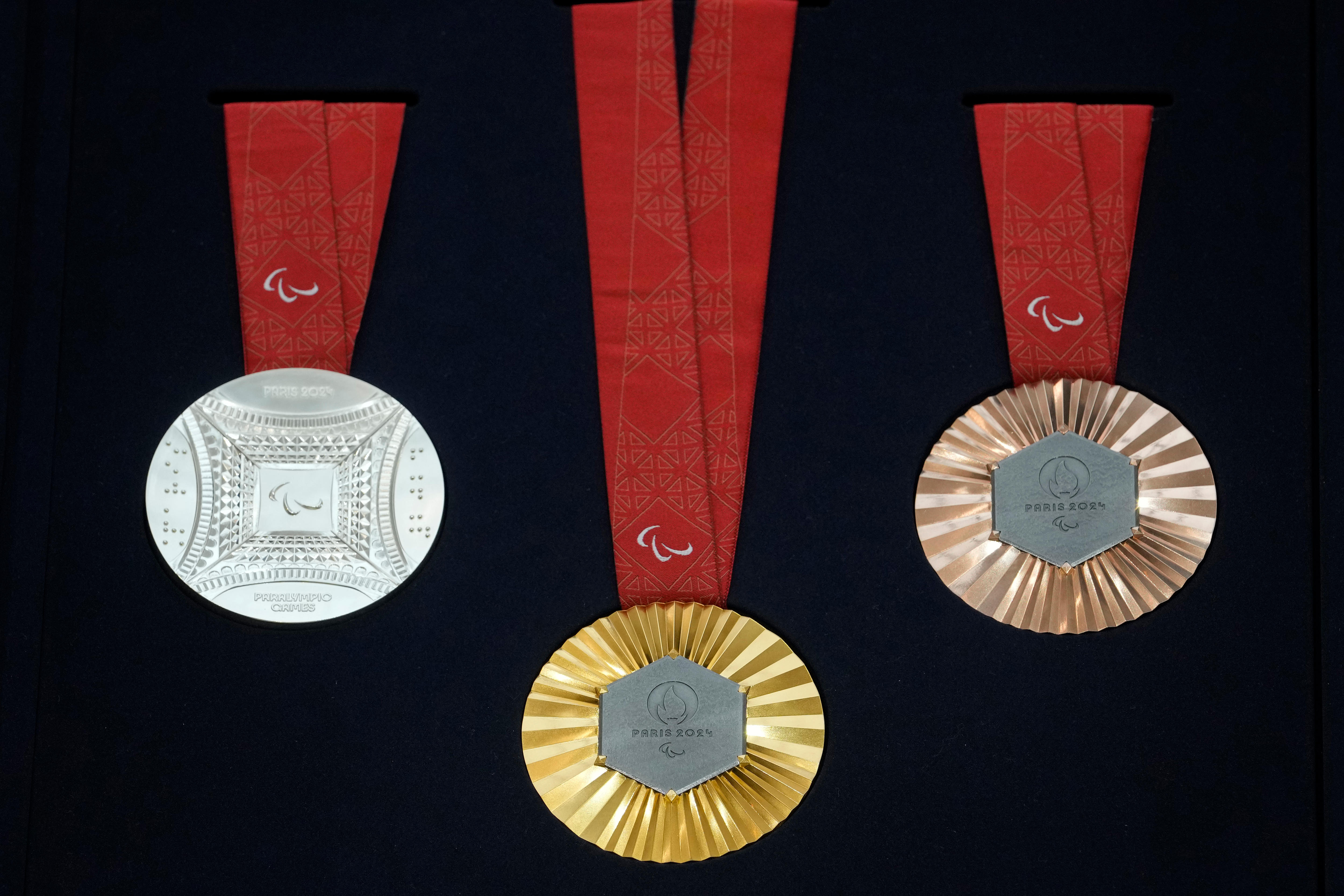 A group of Paralympic medals - silver, gold and bronze left to right - are shown against a dark background.