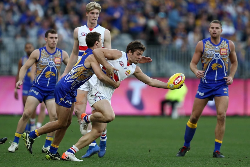 Josh Dunkley of the Bulldogs is tackled by Jamie Cripps of the Eagles.