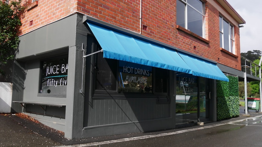 A red brick building with a grey shop front with bright blue awning.