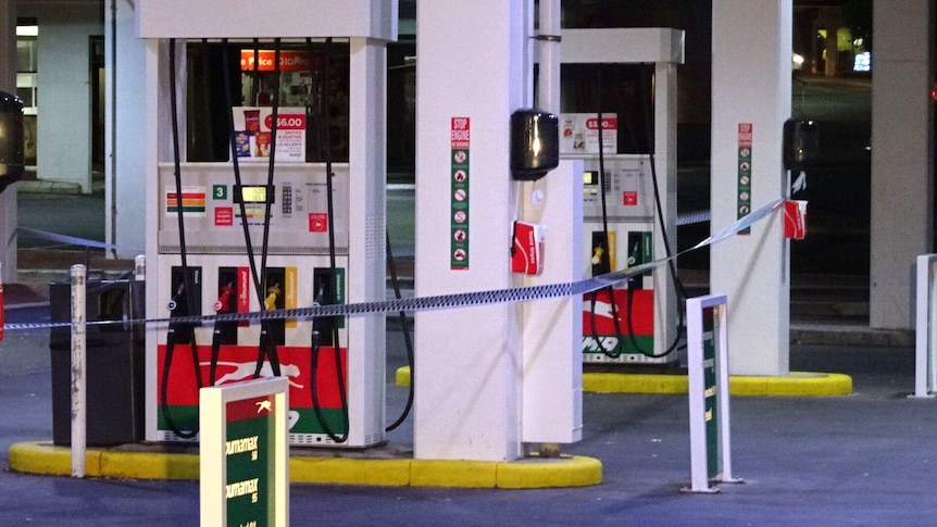 Petrol pumps at a service station wrapped in police tape.