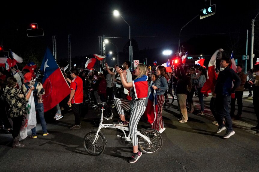 Supporters are pictured cheering while walking through the street with Chilean flags