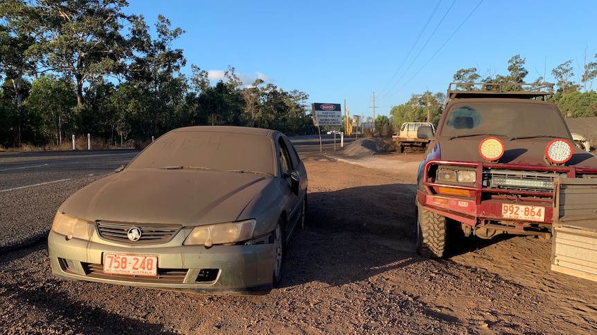 Two cars covered in dust.