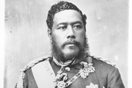 A black and white photo of the King wearing a generals' suit with a sash and several badges.