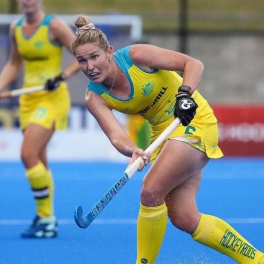 A woman plays hockey in the green and gold.