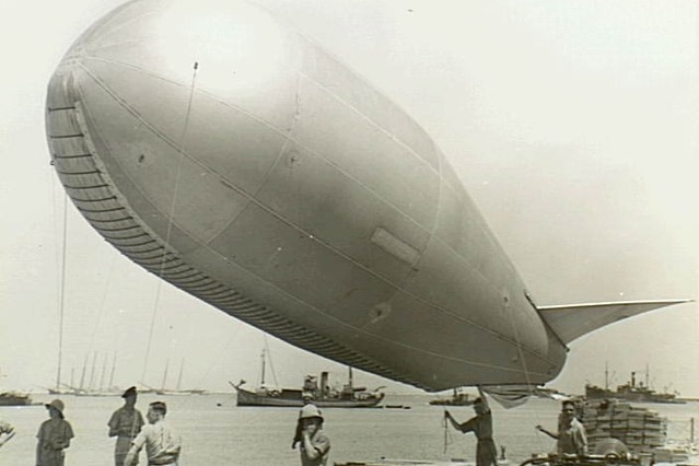 Historical image of a barrage balloon is deployed by Royal Air Force personnel from the beach.