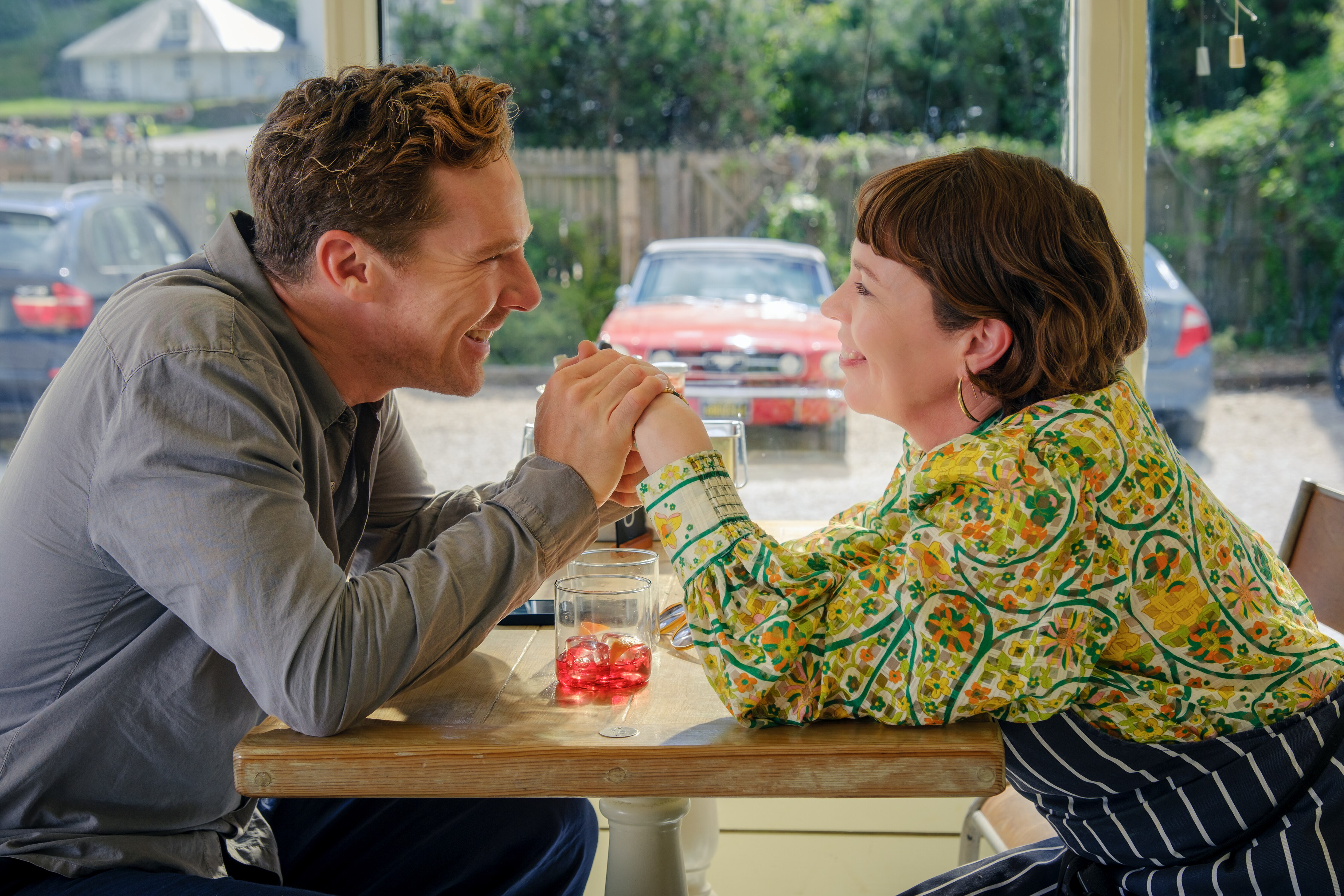 A man and a woman hold hands over a diner table 