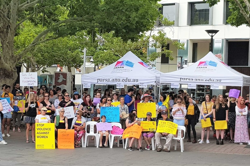 A crowd of people holding protest signs