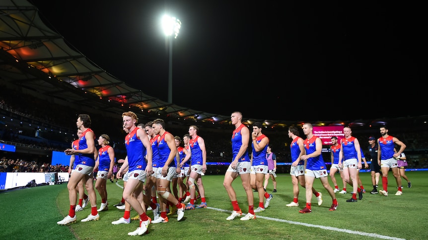 Melbourne Demons AFL players walk off the Gabba after a game against Brisbane Lions.