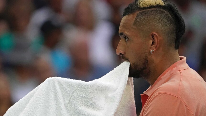 Nick Kyrgios holds a towel in his mouth
