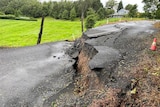 An asphalt road with a major crack after a land slide.