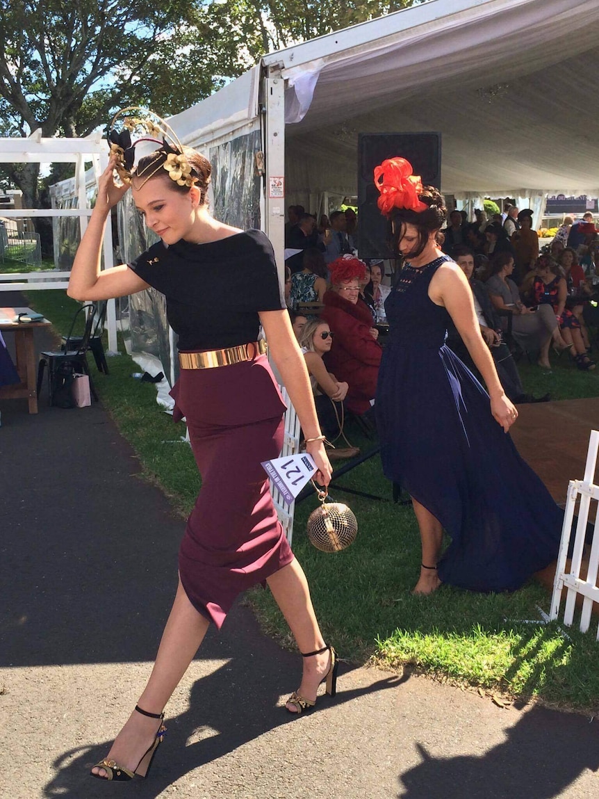 A young woman walks out of a Fashions on the Field competition smiling.