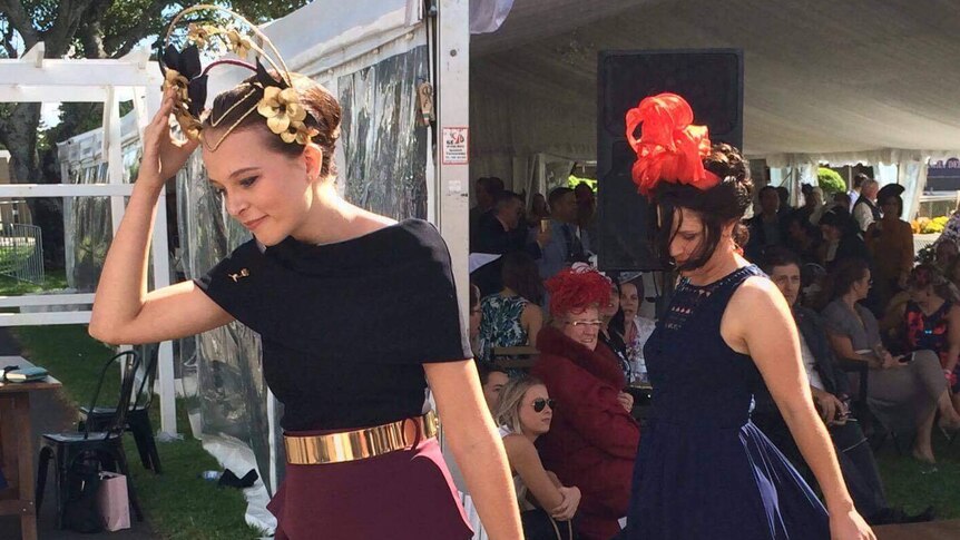 A young woman walks out of a Fashions on the Field competition smiling.