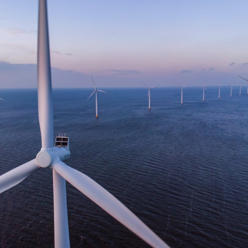 Artist's impression of eight large, white wind turbines standing in a row in the ocean.