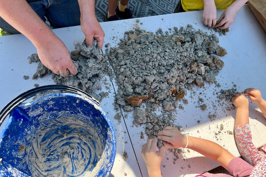 people kneading mud to help make the canoe.