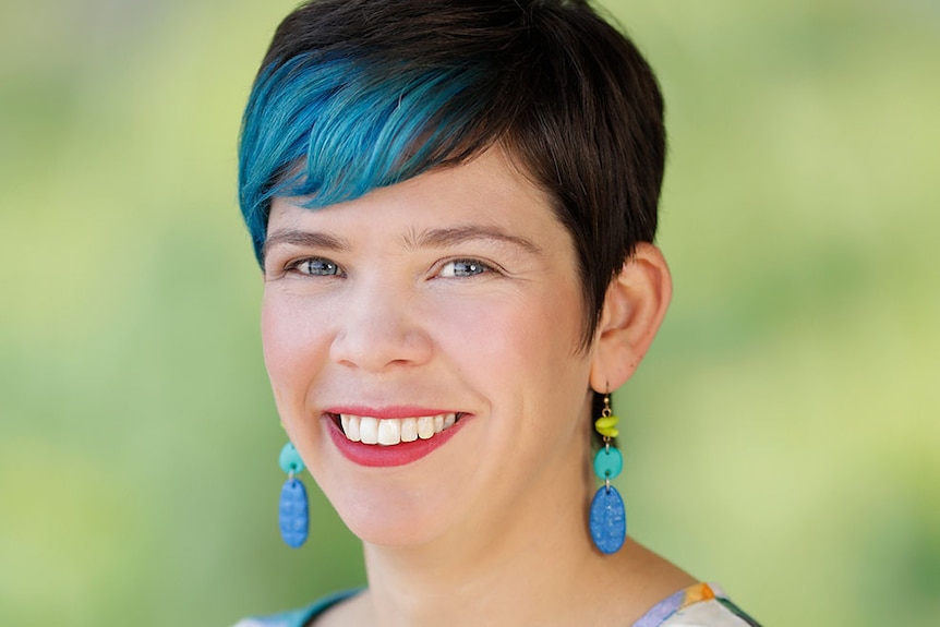 A smiling woman with black and green hair